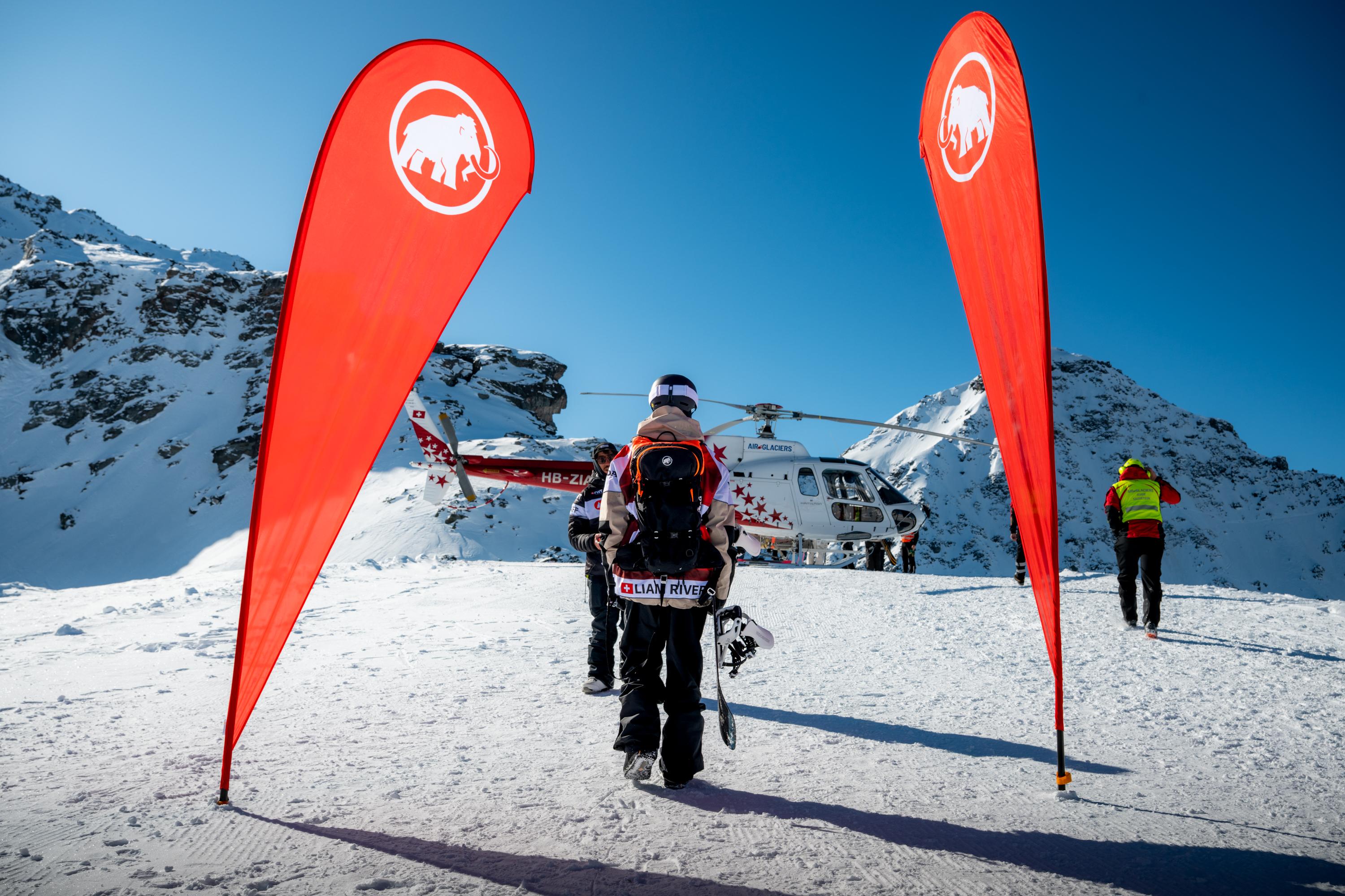 Snow-covered mountain range with peaks illuminated by the warm glow of the setting sun against a clear sky, perfect for Mammut mountaineering gear.