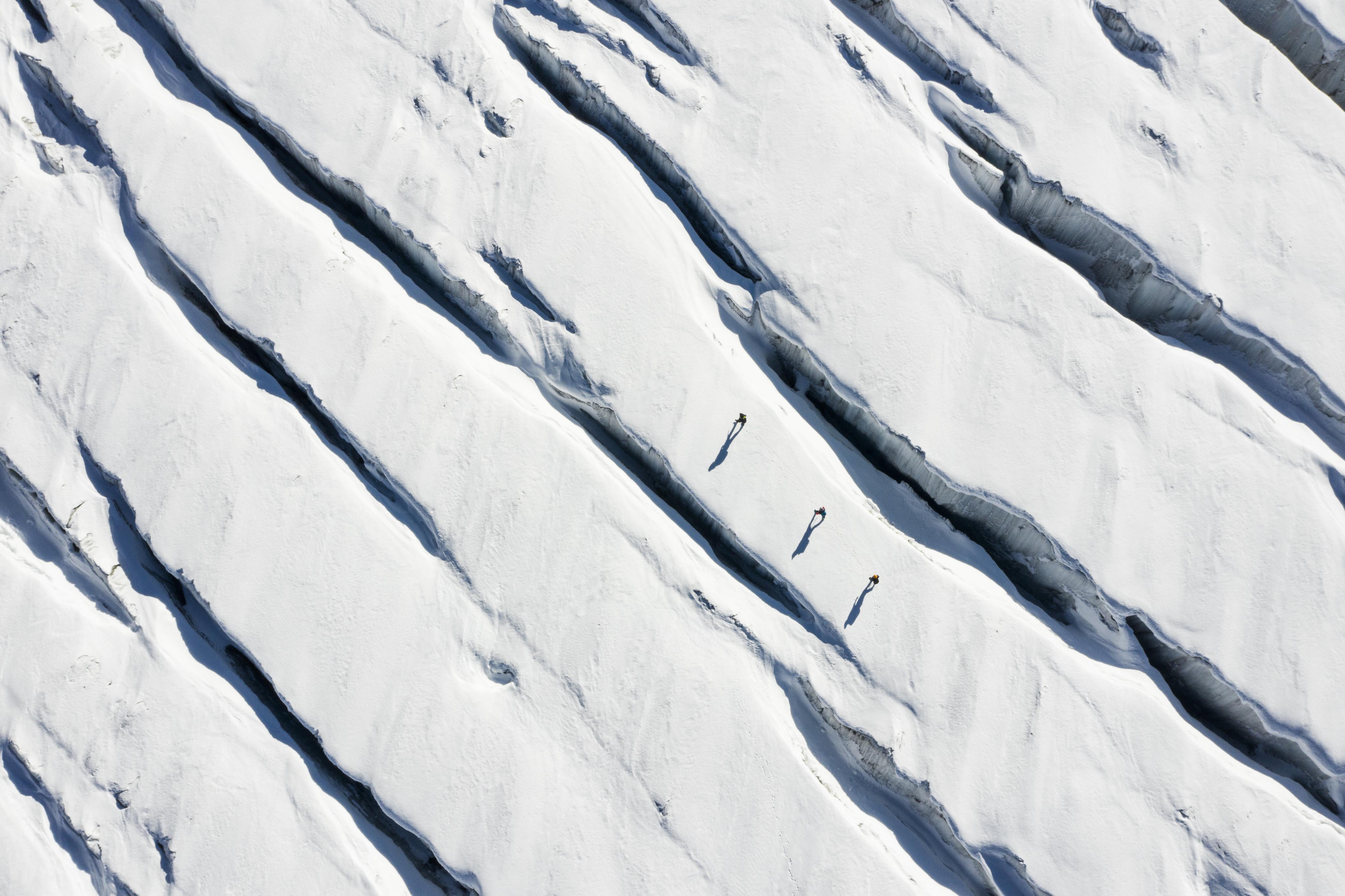 Three people walking on a glacier