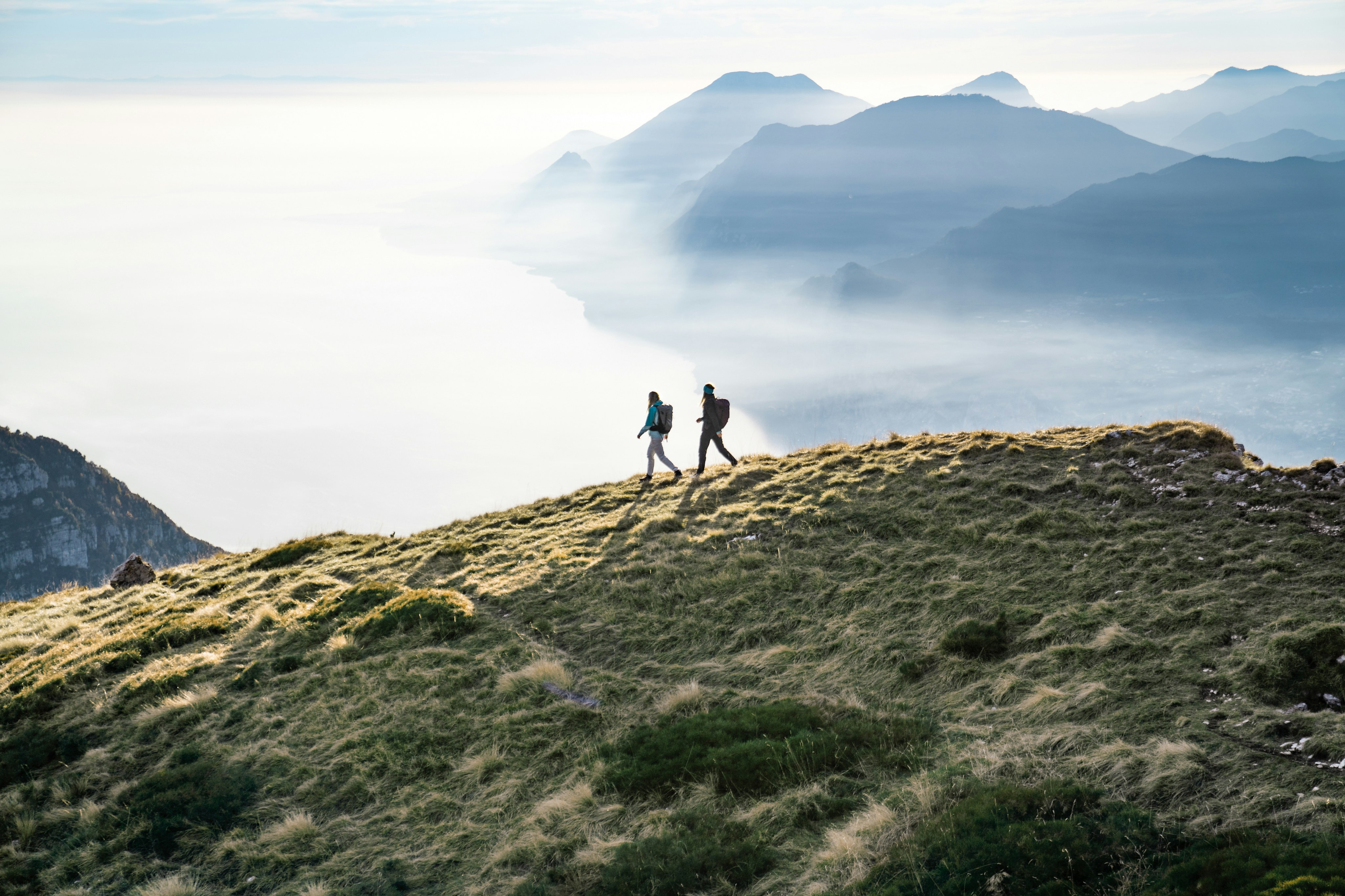 Two women hiking on a mountain in the distance 