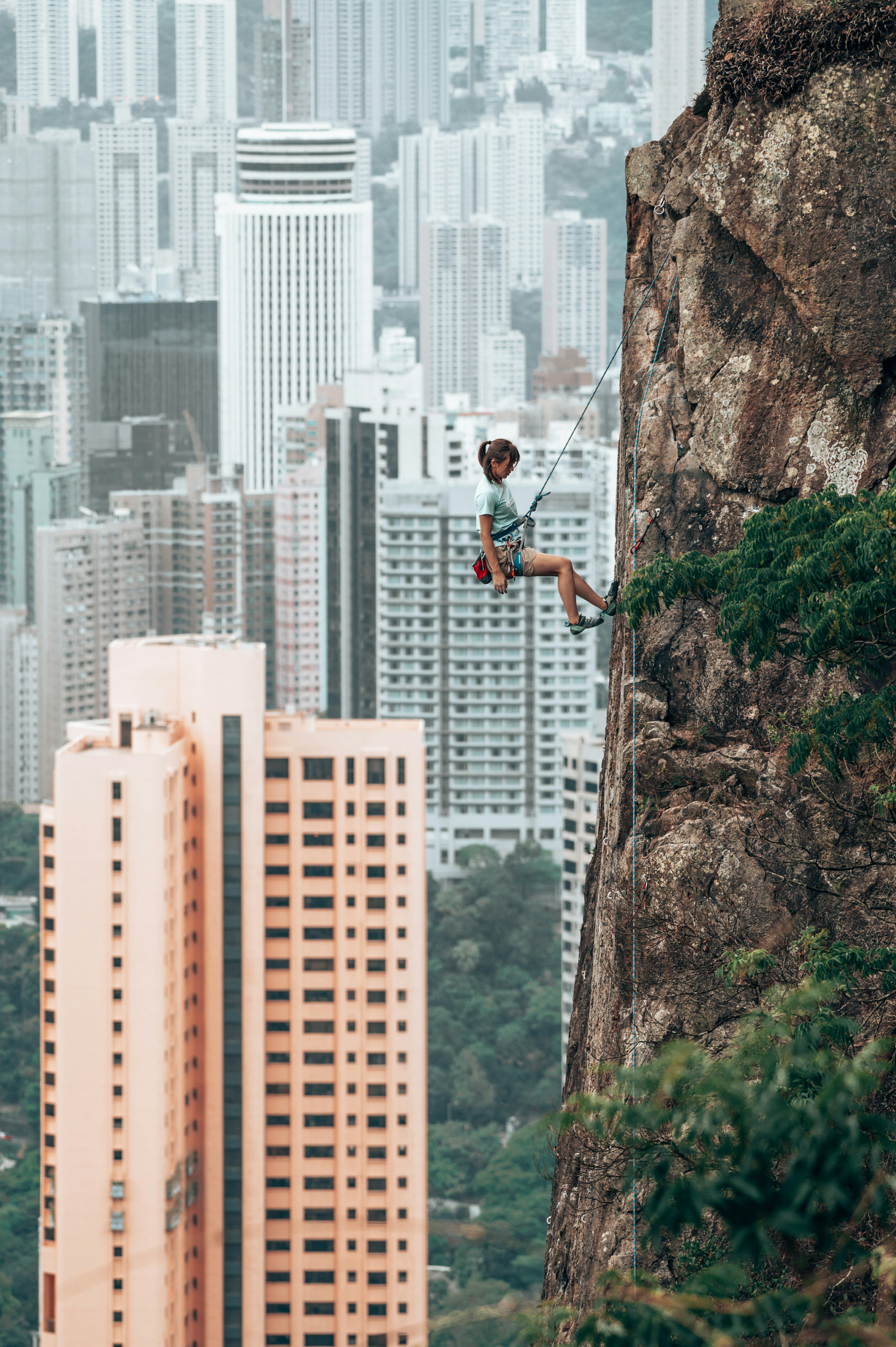 Woman climbing in front of of a city skyline