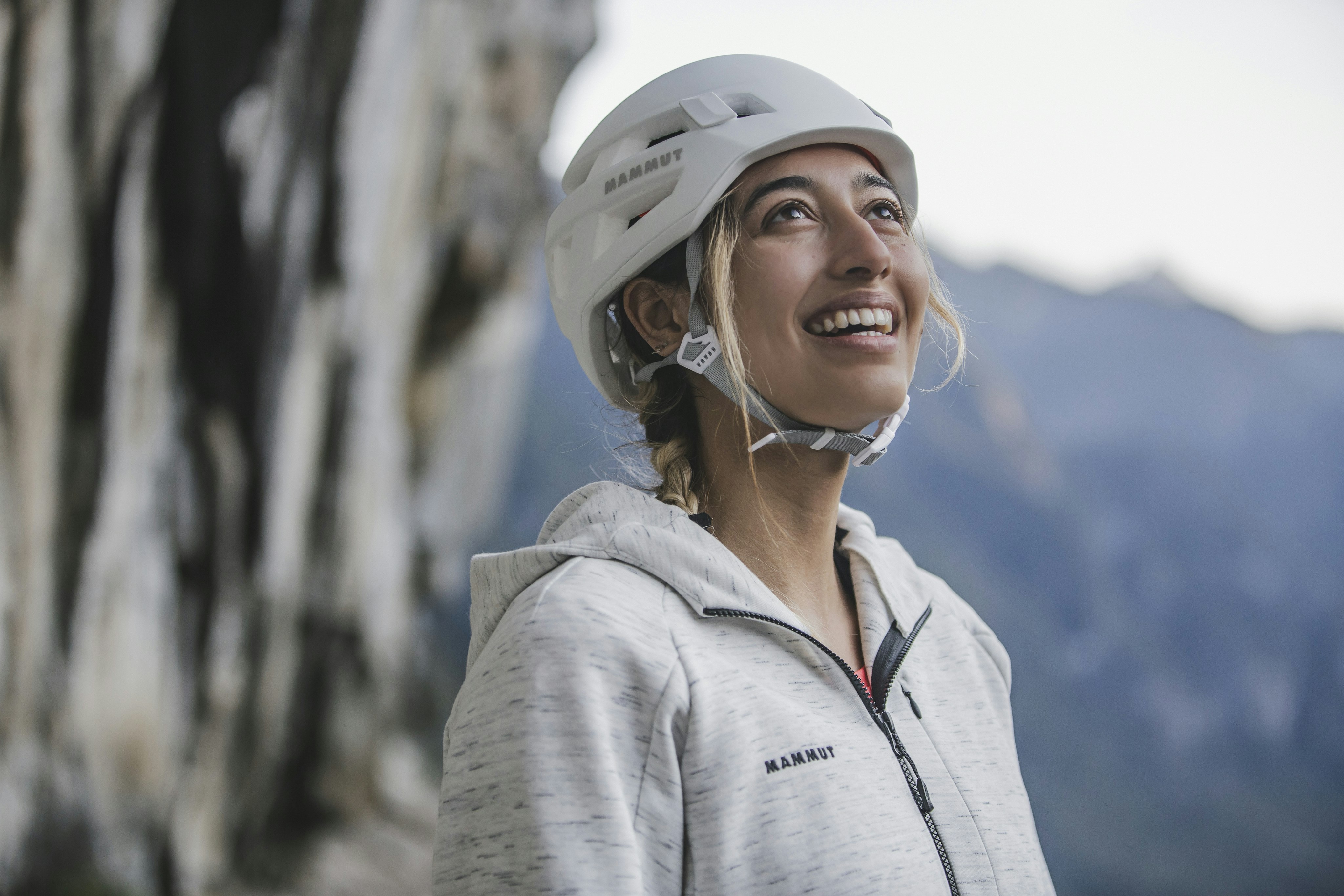 Woman with Mammut climbing helmet looks up and smiles