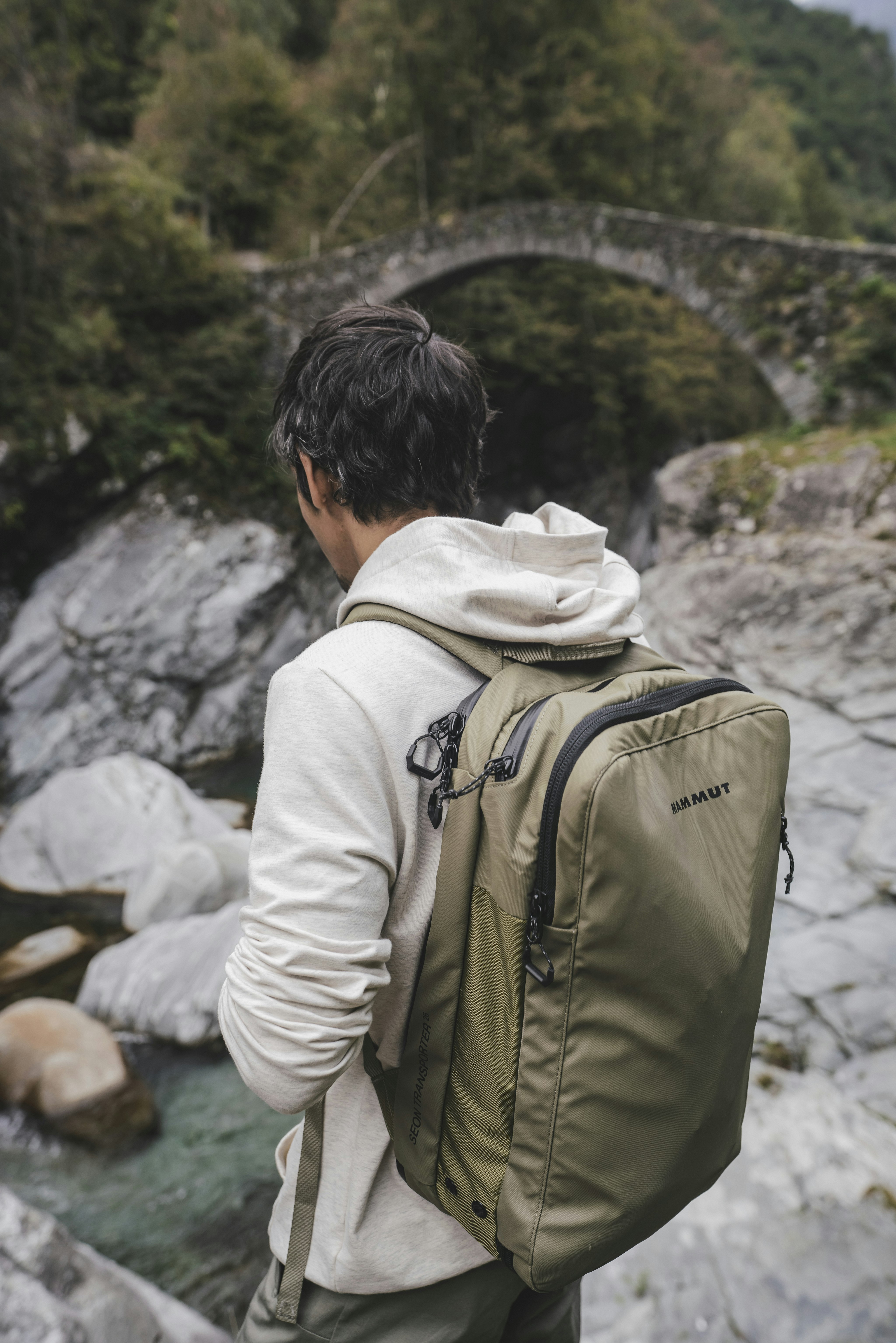 Man carrying mammut backpack in front of a creek 