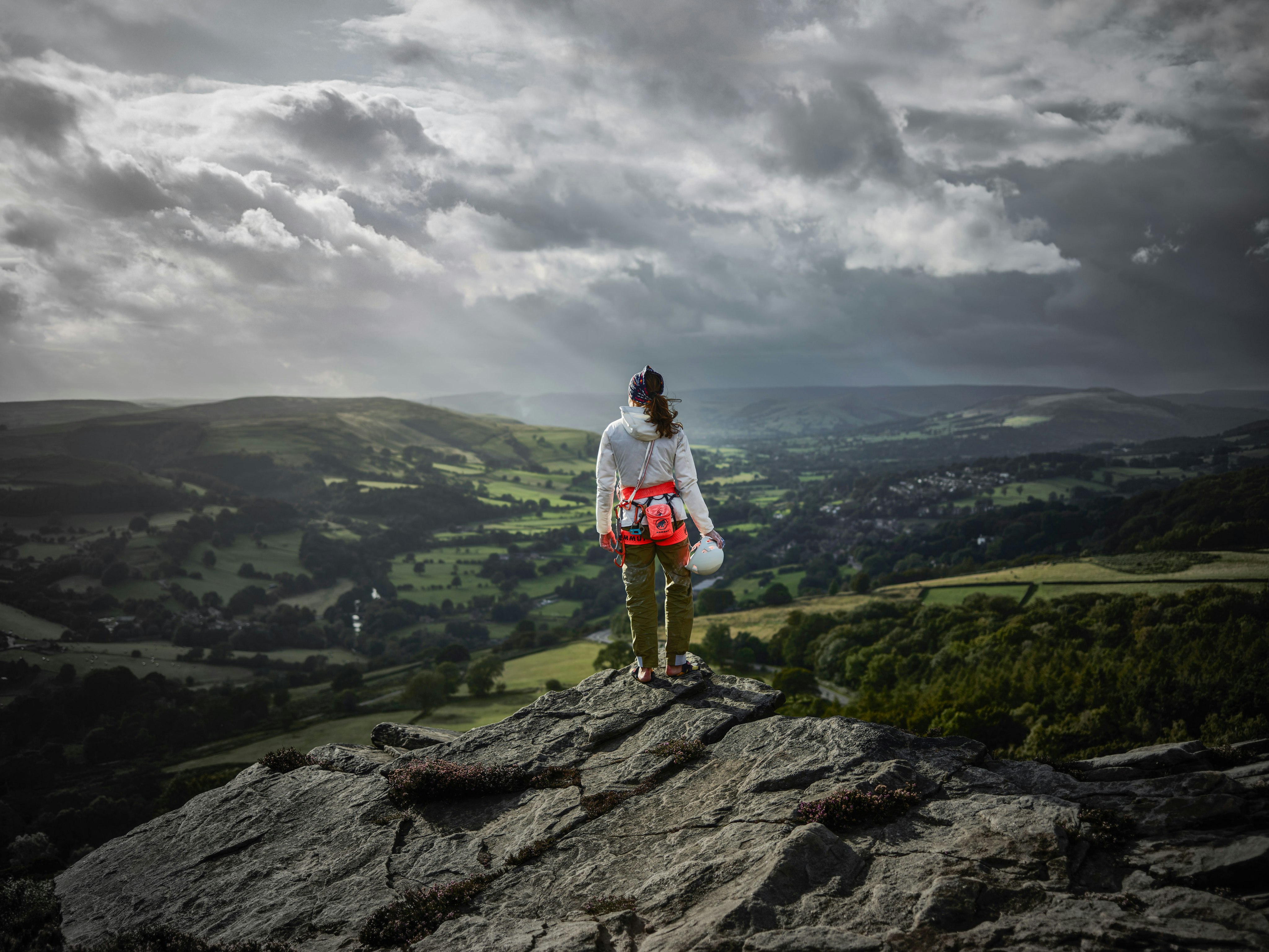 Woman in Mammut outfit stands on a rock and looks into the distance