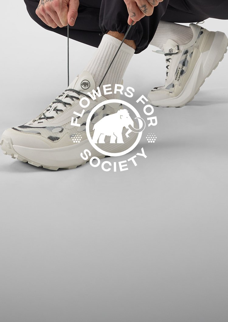 White and gray Mammut sneakers worn with black pants, featuring a "Flowers for Society" logo overlay on the image.