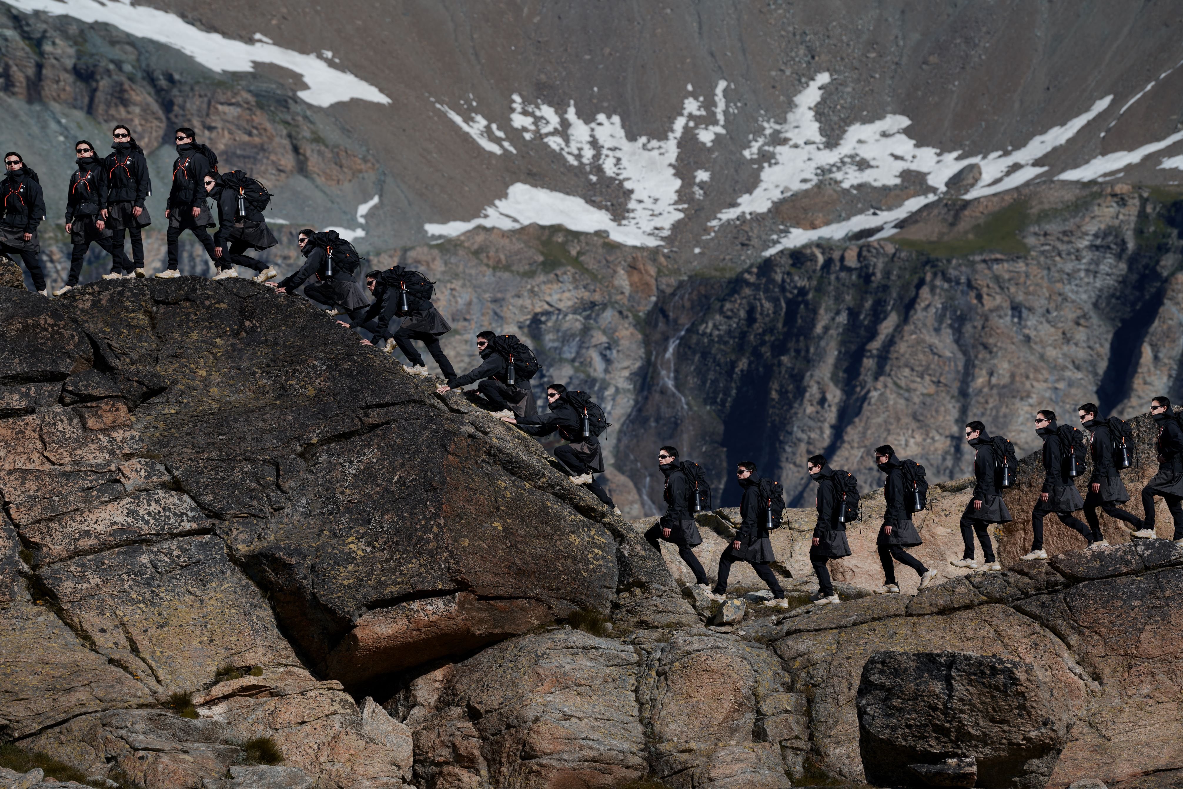 A climber in Mammut gear scaling a rocky hill with mountainous backdrop, showcased in multiple stages of the ascent.