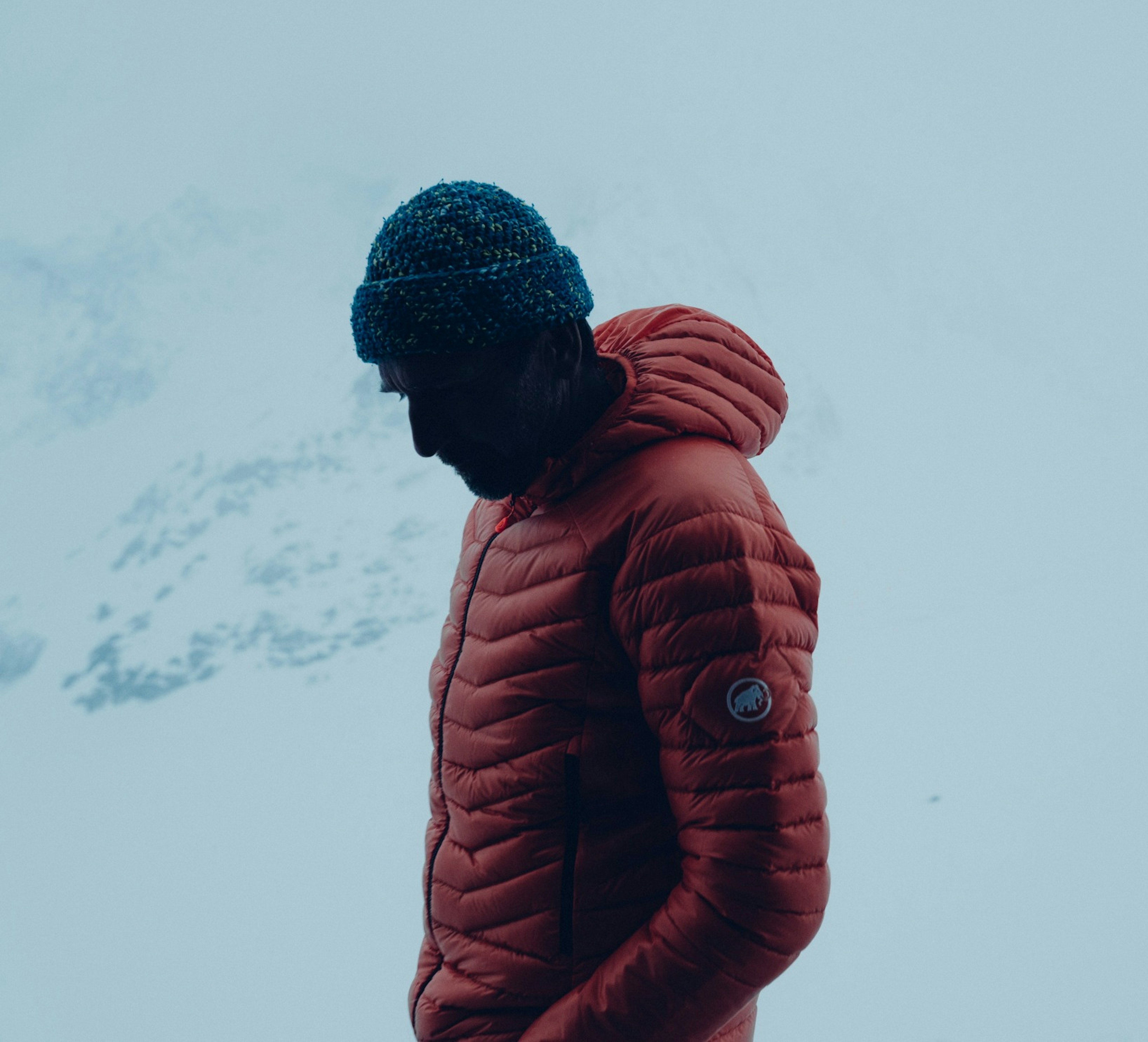 Homme debout devant des montagnes couvertes de neige.