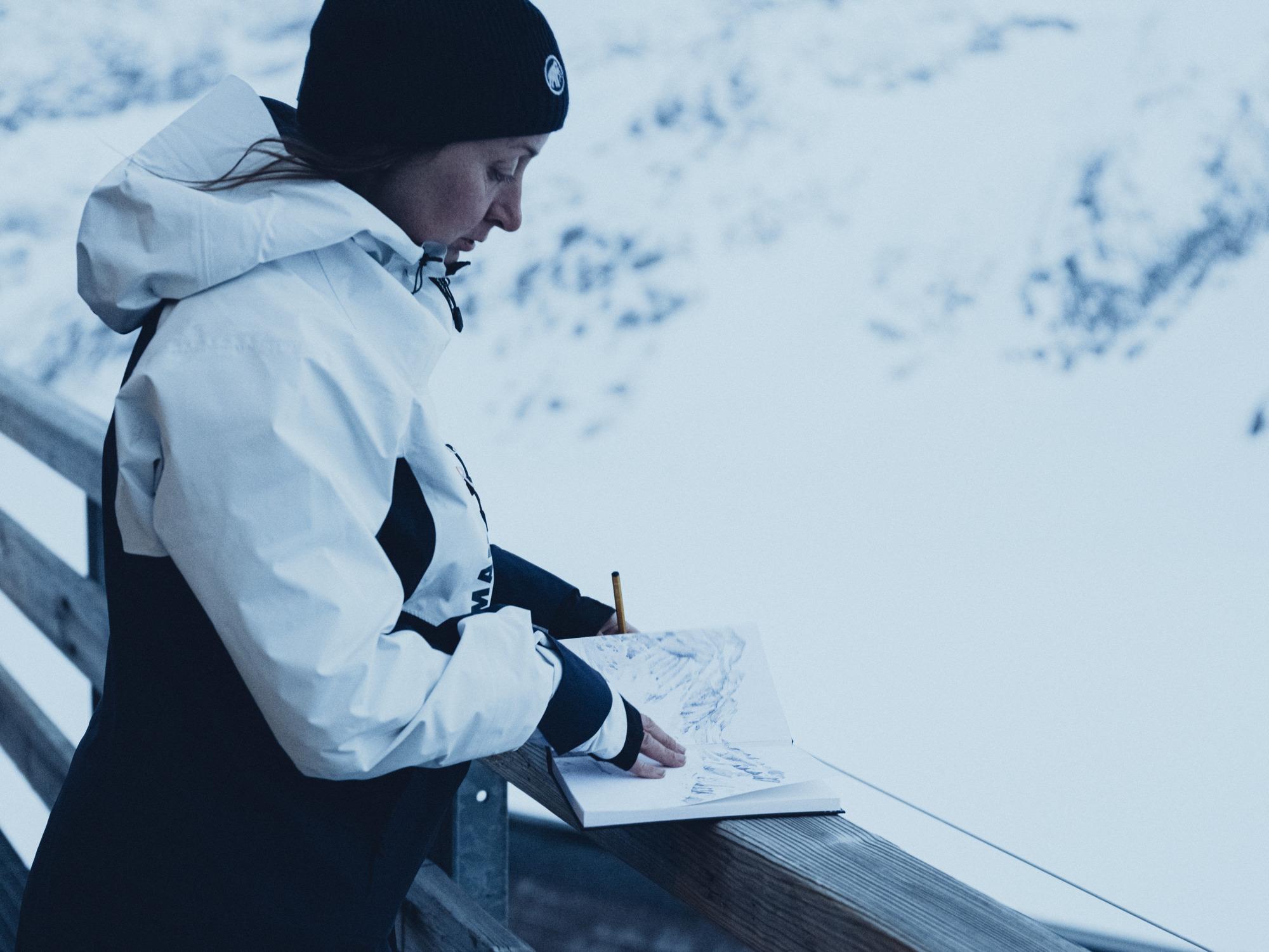Woman standing on a terrace and drawing the mountains.