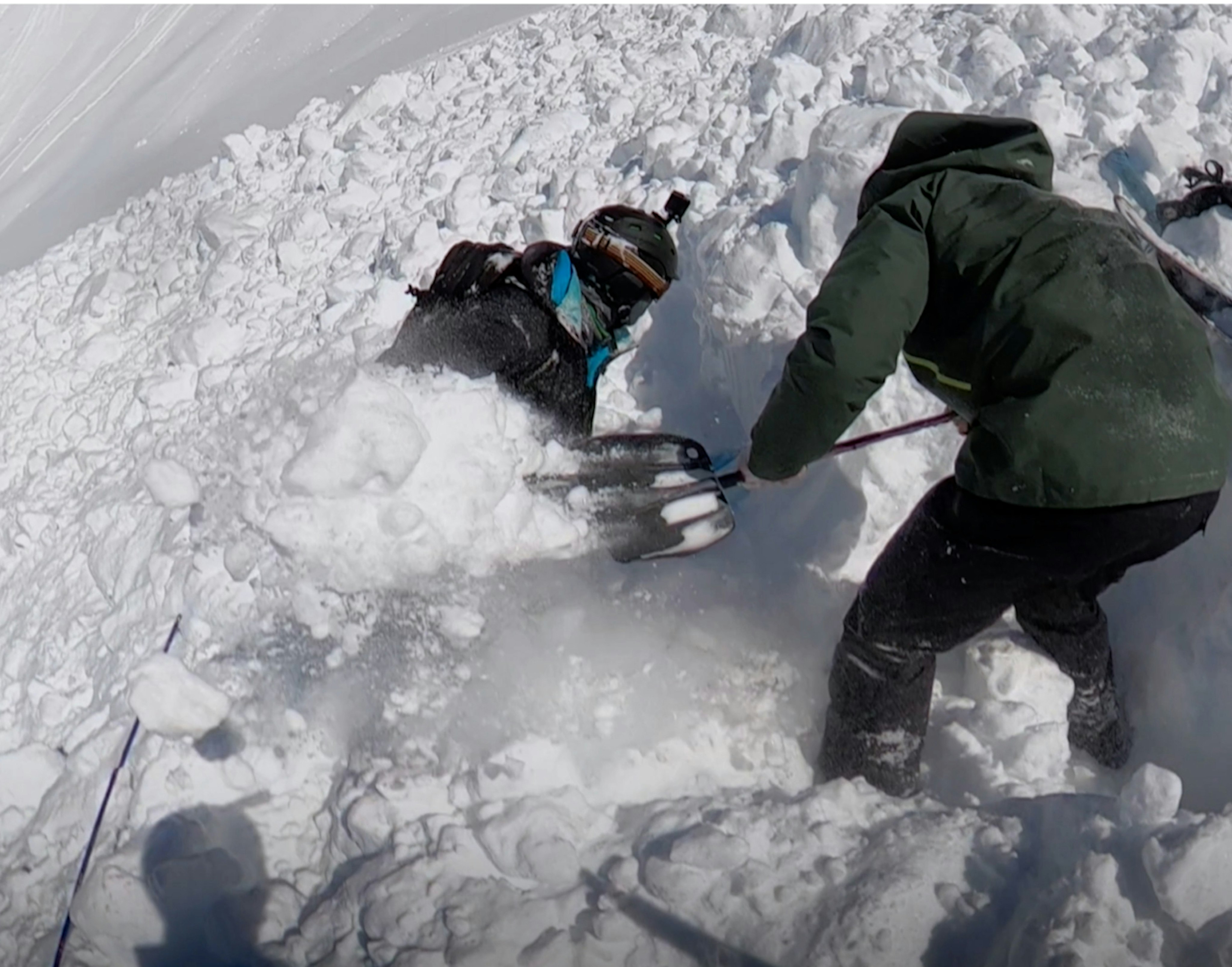 Two men digging with shovels in an avalanche cone. 