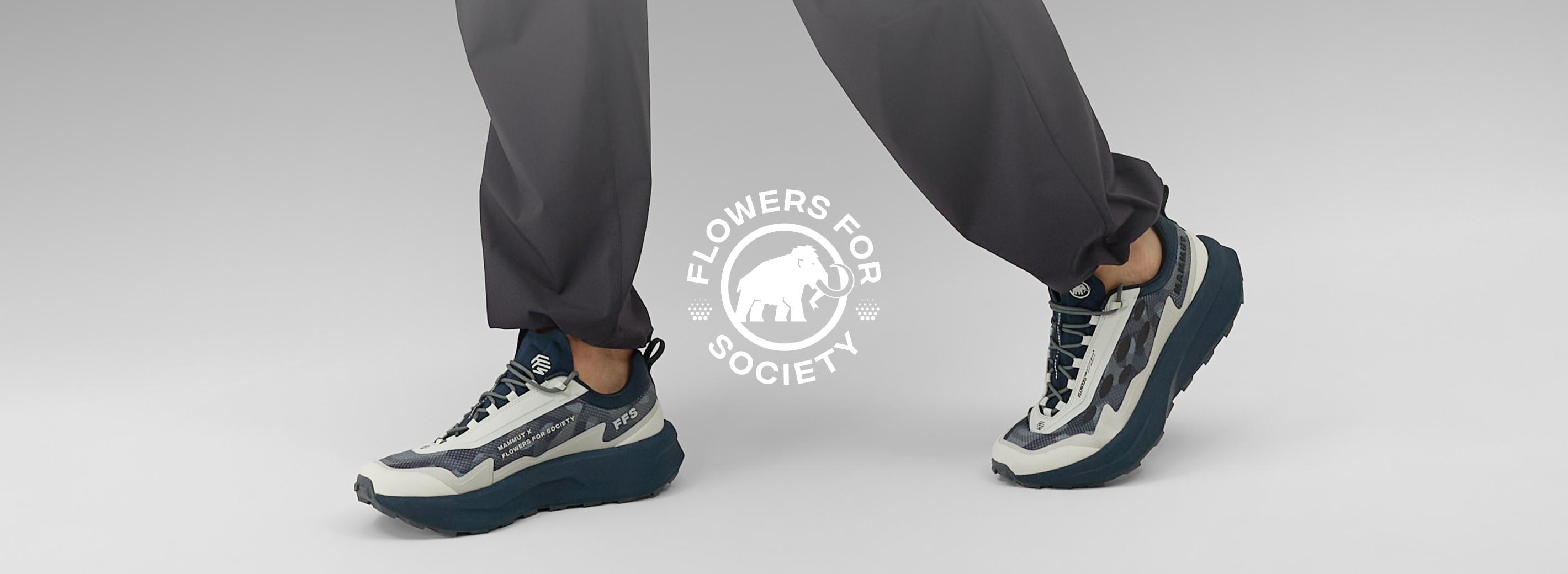 Person wearing chunky white and navy sneakers styled for Mammut, with "Flowers for Society" logo visible in the background.