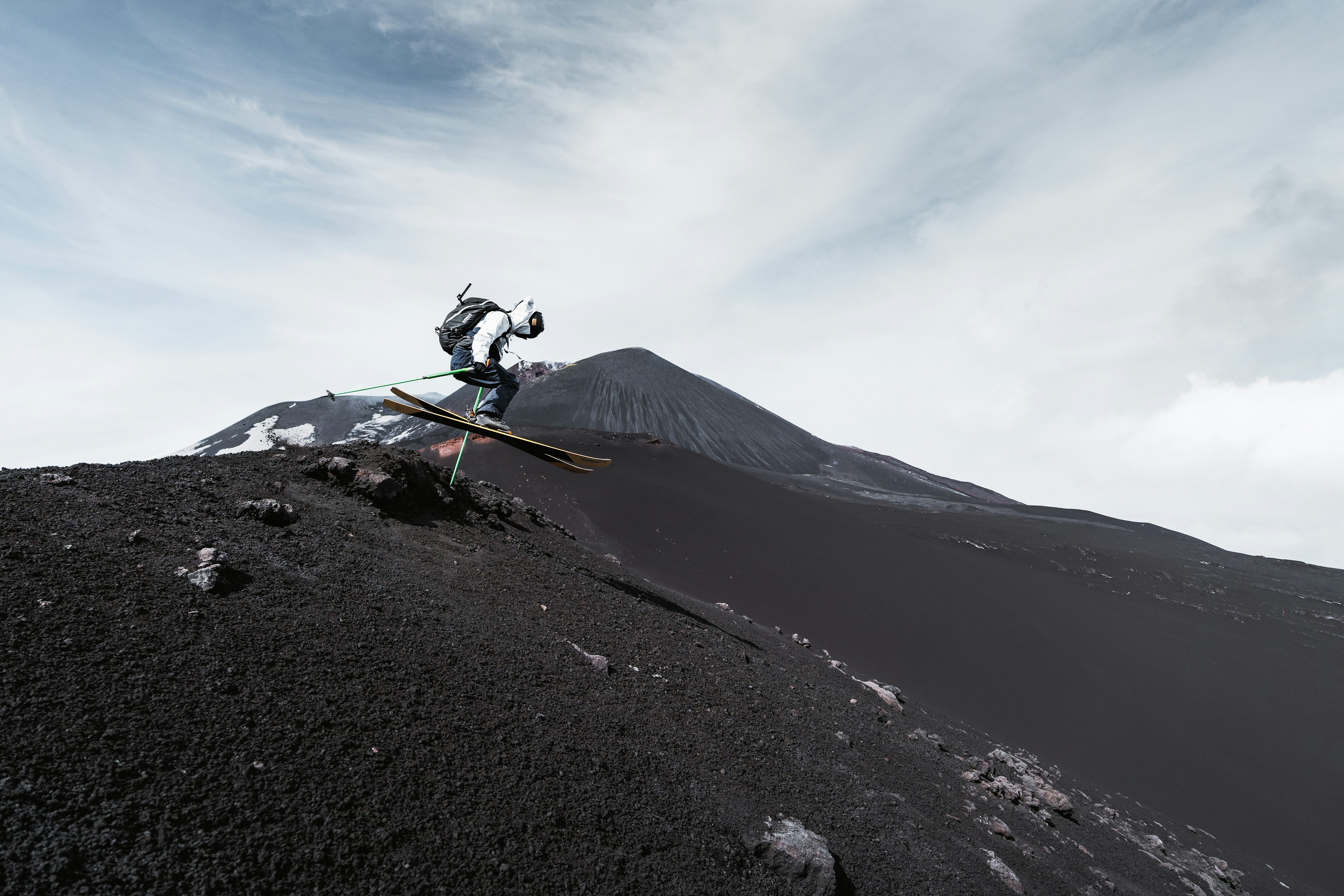 Skier auf einem Vulkan mit schwarzer Asche.