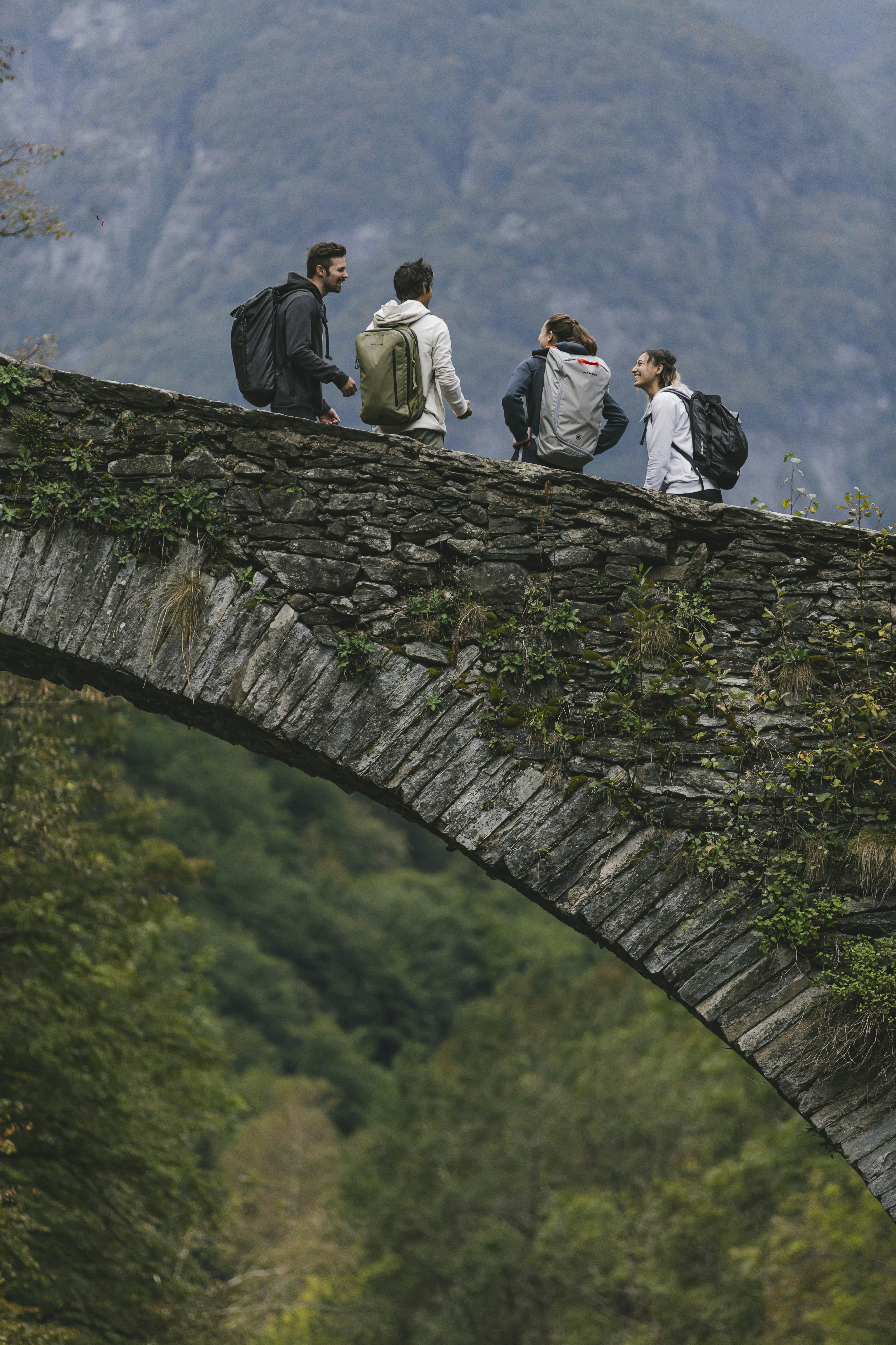 Four people standing on bridge with mammut backpack