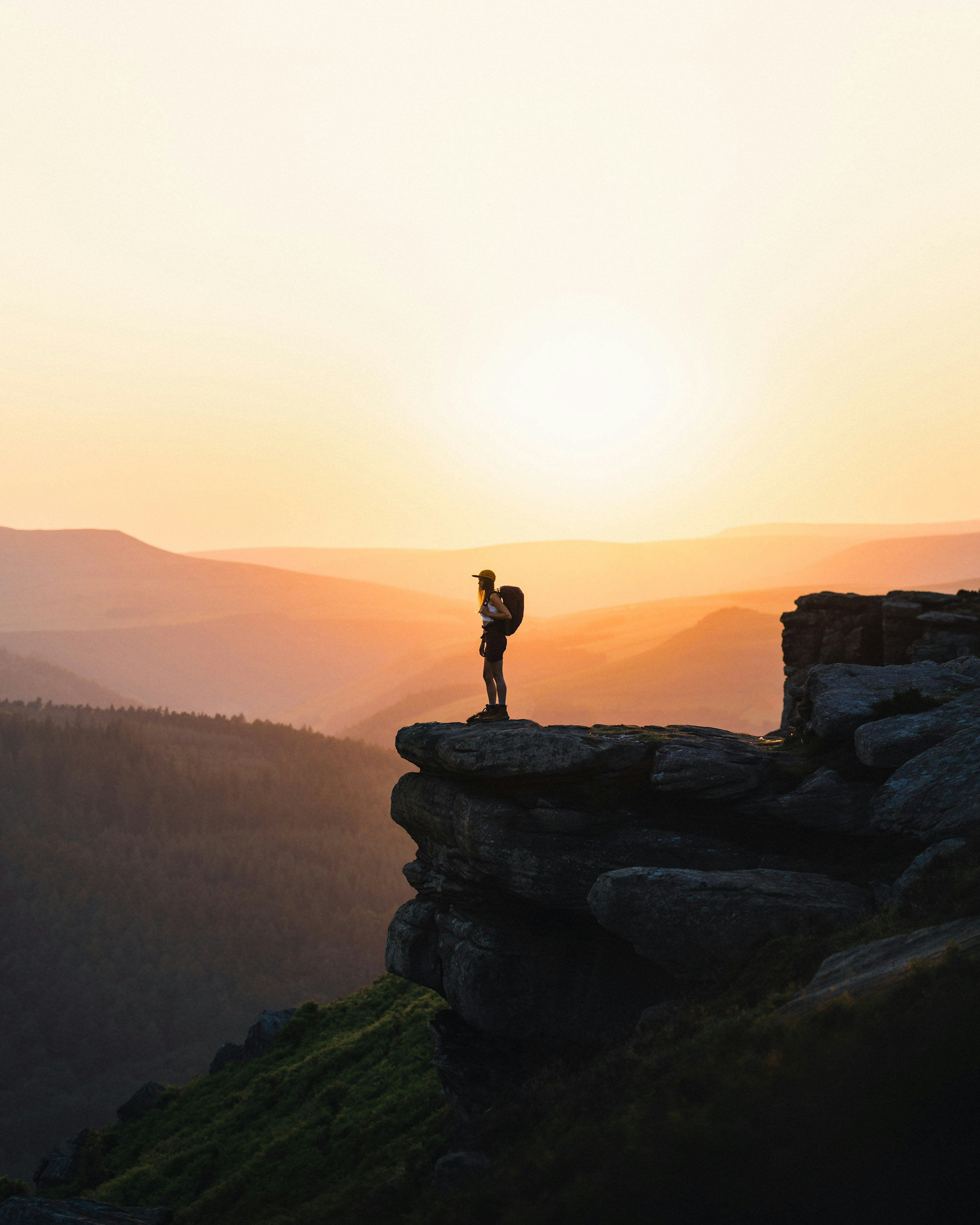 Woman standing on cliff for sunset