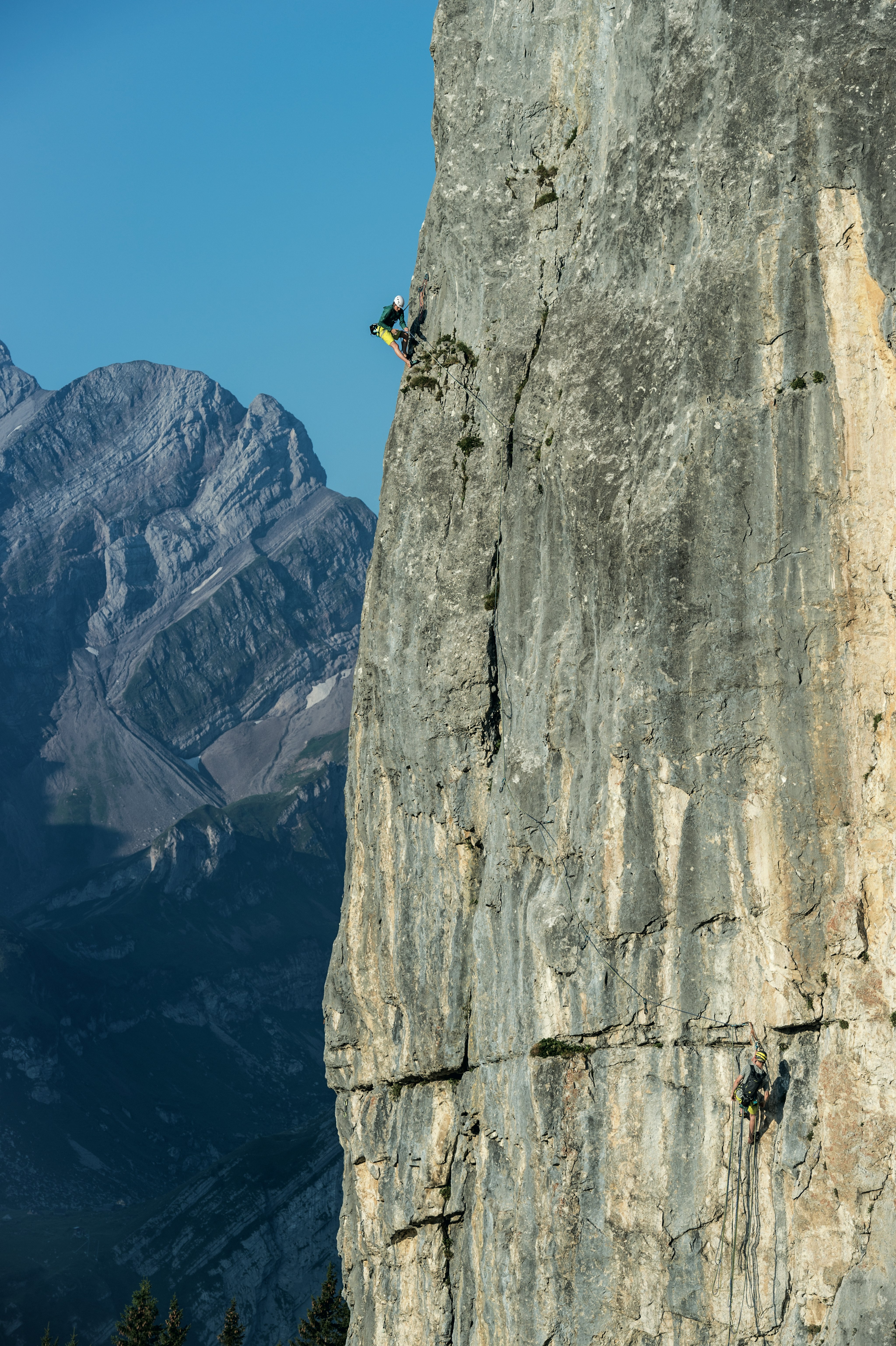 Kletterer hängt gesicher an einer hohen Felswand