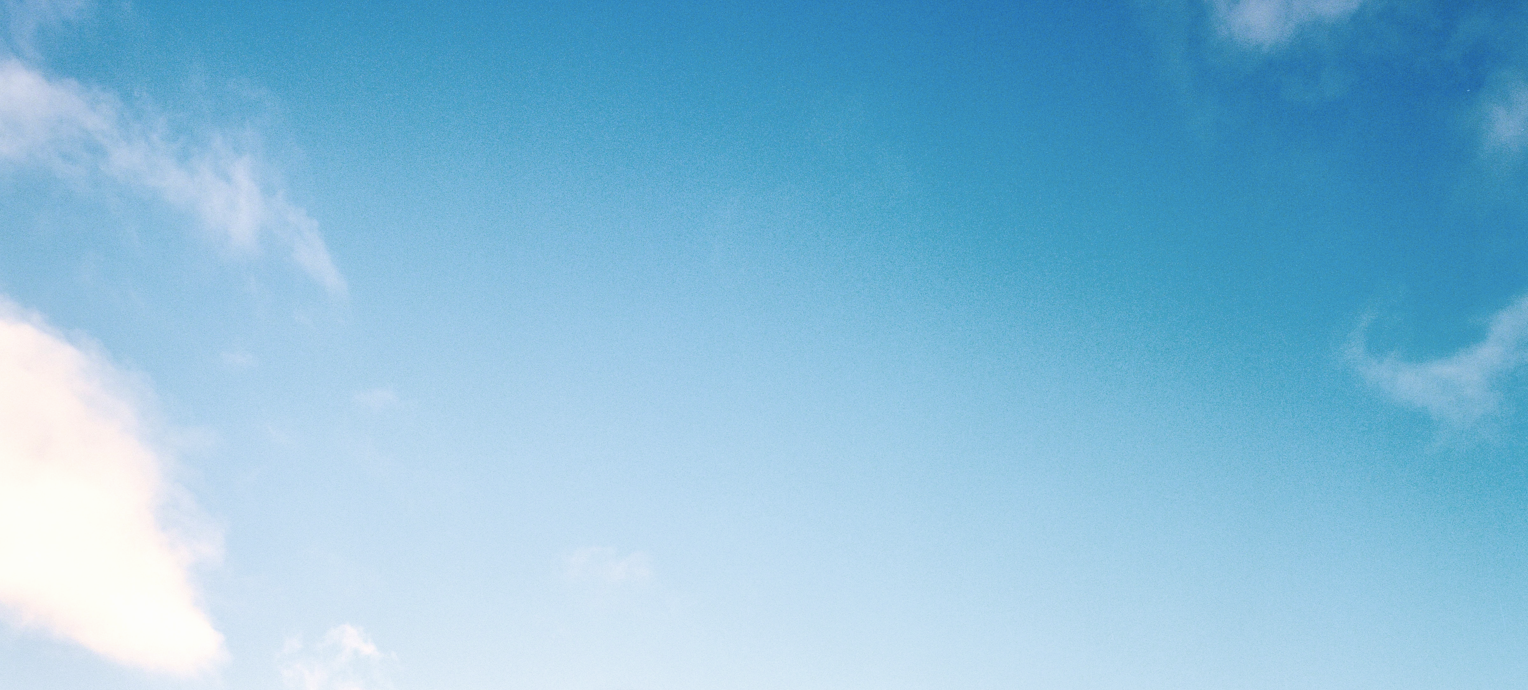 A clear blue sky with a few scattered white clouds on the left and right edges, providing an ideal backdrop for Mammut's high-performance mountaineering gear.