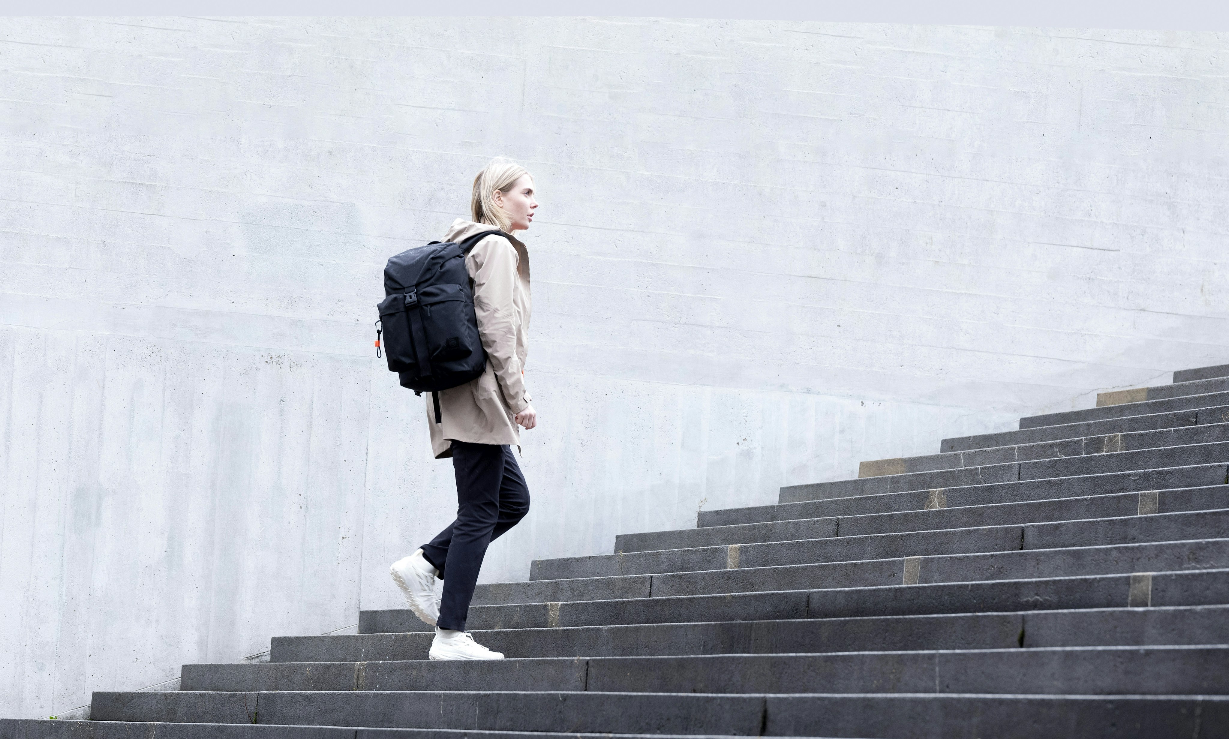 Woman with backpack walking up stairs.