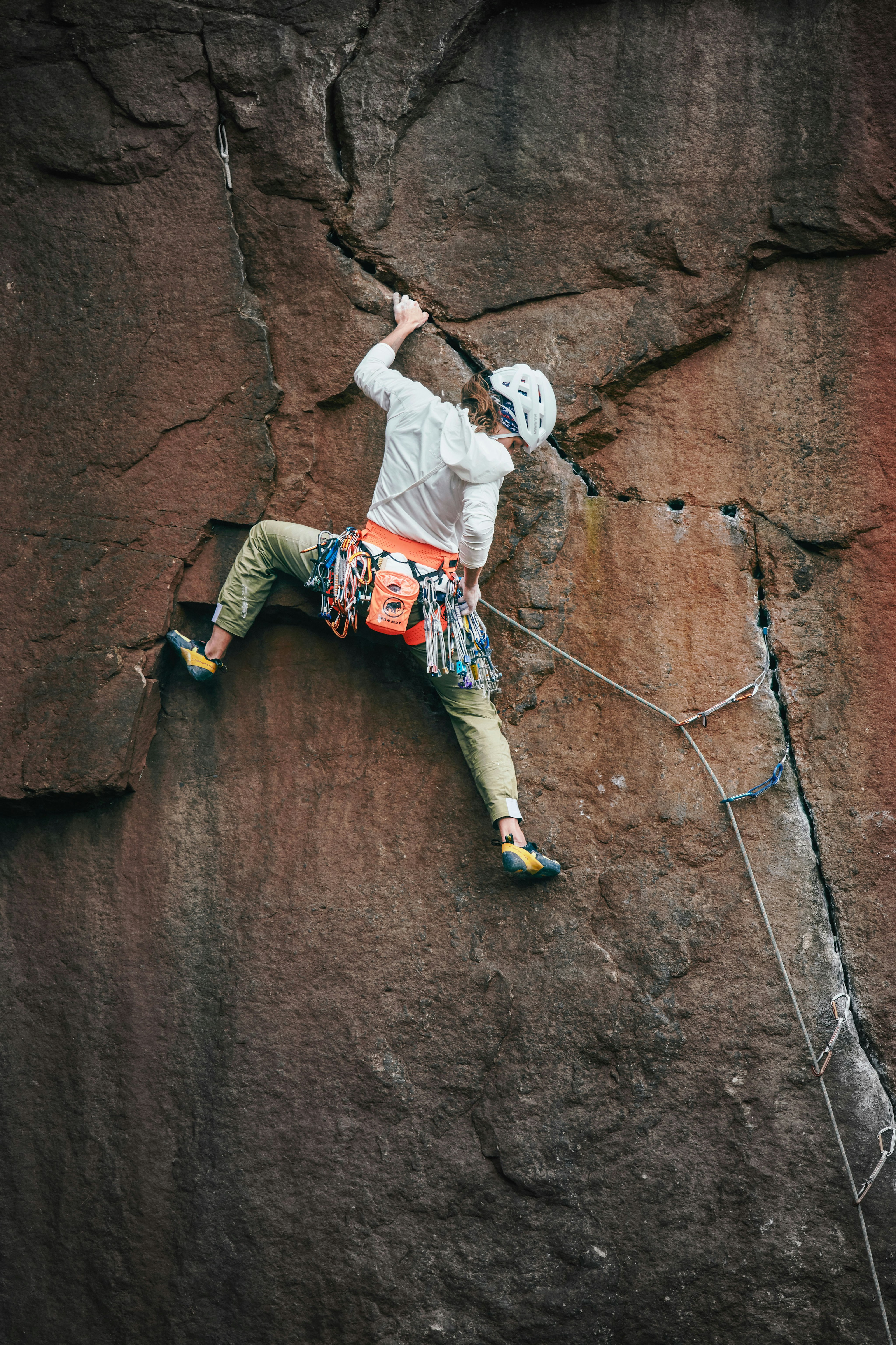 Close up woman climbing on rock and reaching into chalk bag